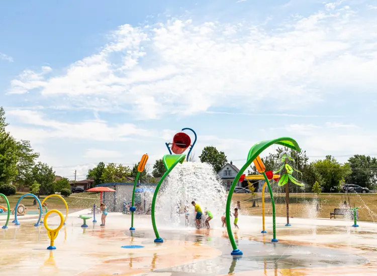 A large spray pad with kids playing in the summer
